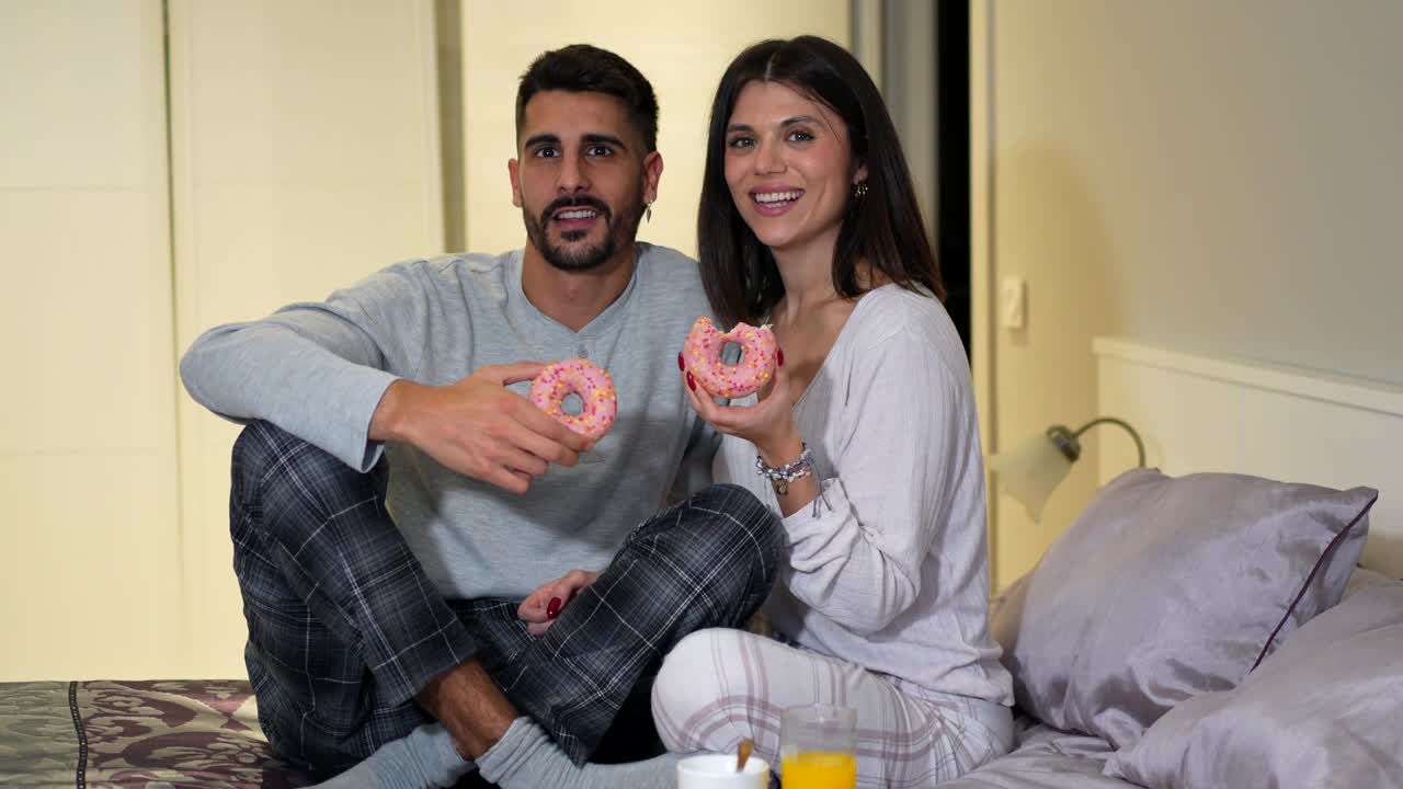 Couple eating donuts in bed