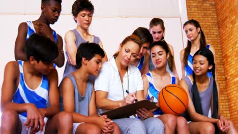 coach instructing a students in basketball court