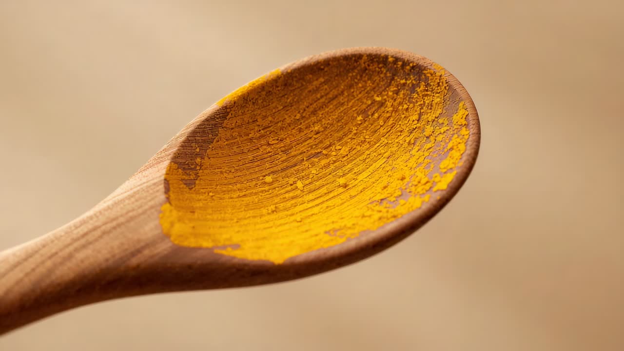 Camera adjusting focus, showing wooden spoon with yellow powder on prep desk, revealing texture