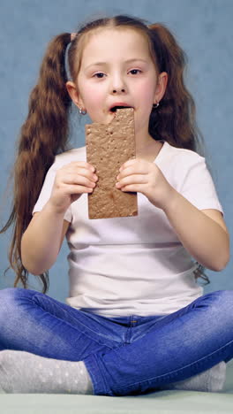 girl eating chocolate bar. girl sitting on the table and eating chocolate