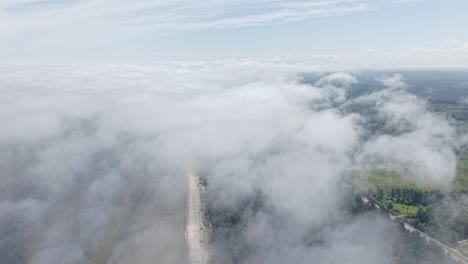 clouds hover over coastal area with faint road and sea partially visible from above