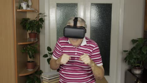 grandmother in virtual headset glasses watching video in vr helmet training box, shows fist fight