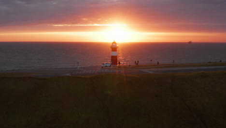 The-lighthouse-of-Westkapelle-during-a-bright-orange-sunset,-with-a-lot-of-wind