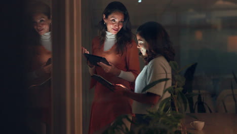 Two Women Discussing Using Tablets at Night