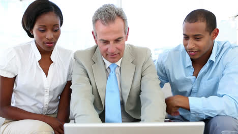 Salesman-talking-to-customers-on-the-couch-showing-them-laptop