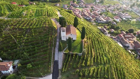 Aerial-landscape-view-of-the-famous-prosecco-hills-with-vineyard-rows-and-a-small-church,-in-Italy