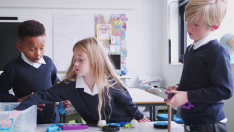 three primary school children working with construction toy in classroom, front view, close up