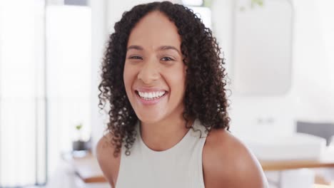 Retrato-De-Una-Mujer-Birracial-Feliz-Con-El-Pelo-Rizado-Oscuro-Sonriendo-En-Casa,-En-Cámara-Lenta