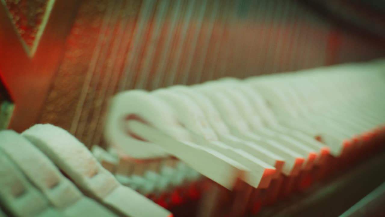 Macro close-up shot panning inside a piano, showing the wooden felt hammers striking the strings to create music