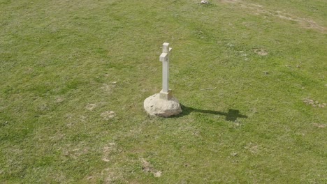 Imágenes-De-Alta-Calidad-Con-Un-Dron-Orbitando-Una-Cruz-De-Piedra-Blanca-En-Un-Prado-Verde