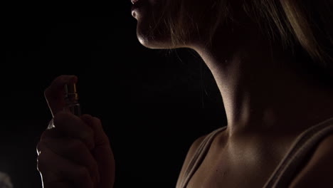 video en cámara lenta de una mujer rociando perfume en su cuello sobre fondo negro