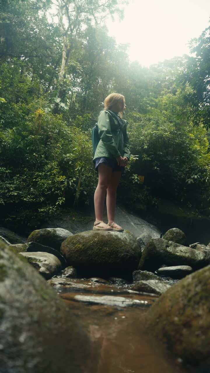 Woman standing on rocks in a forest stream