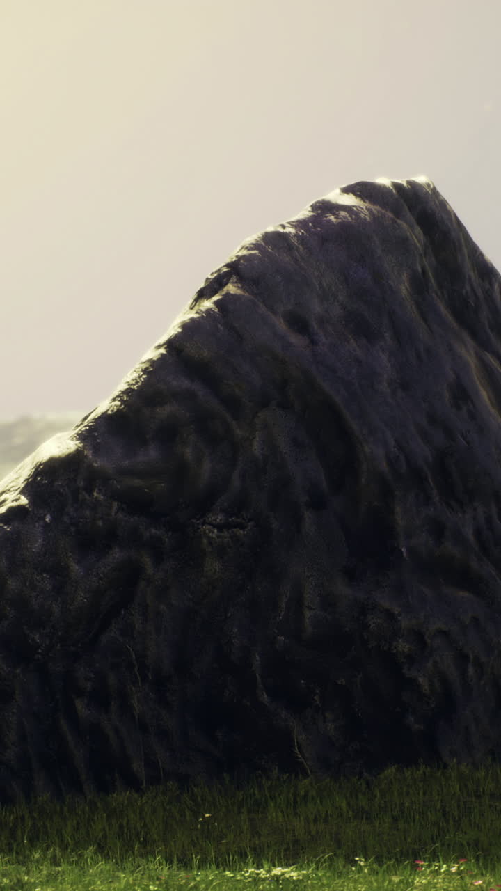 Expansive landscape with large rock formation under soft light