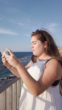 woman on summer holiday taking selfie by the sea, akko old city, israel.