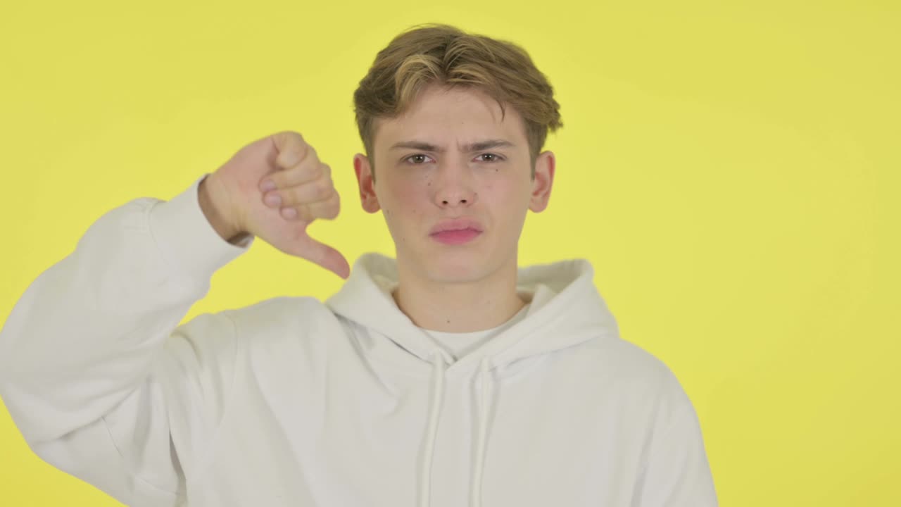 노란색 배경에 젊은이의 엄지손가락 아래로 몸짓