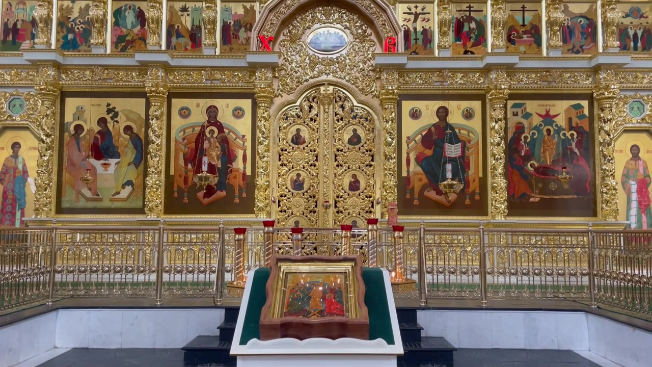 Vista interna della Cattedrale dell'Assunzione nel Cremlino di Astrakhan, Russia, con l'iconostasi dorata e riccamente decorata, icone religiose sacre e un leggio centrale.