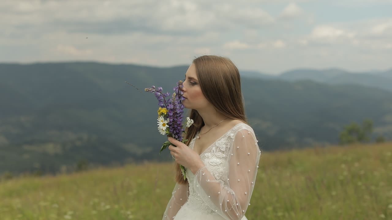 Smuk brud i en hvid kjole med en buket blomster i et bjerglandskab