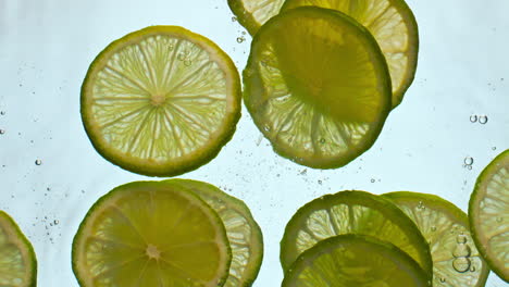 closeup sliced lime water floating in super slow motion. citrus dropped liquid.