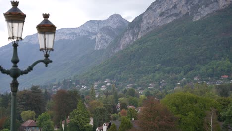 mountain village of annecy in the french alps with rocky hills behind and streetlight left, stable wide shot