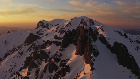 sunset over snow-capped ciucas mountains with orange hues in the sky