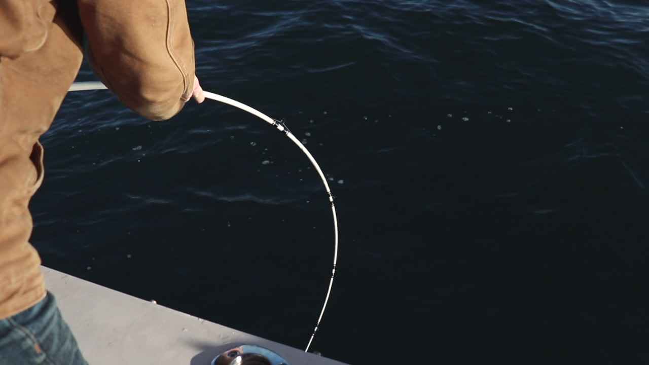 낚싯대에 큰 물고기를 감는 남자