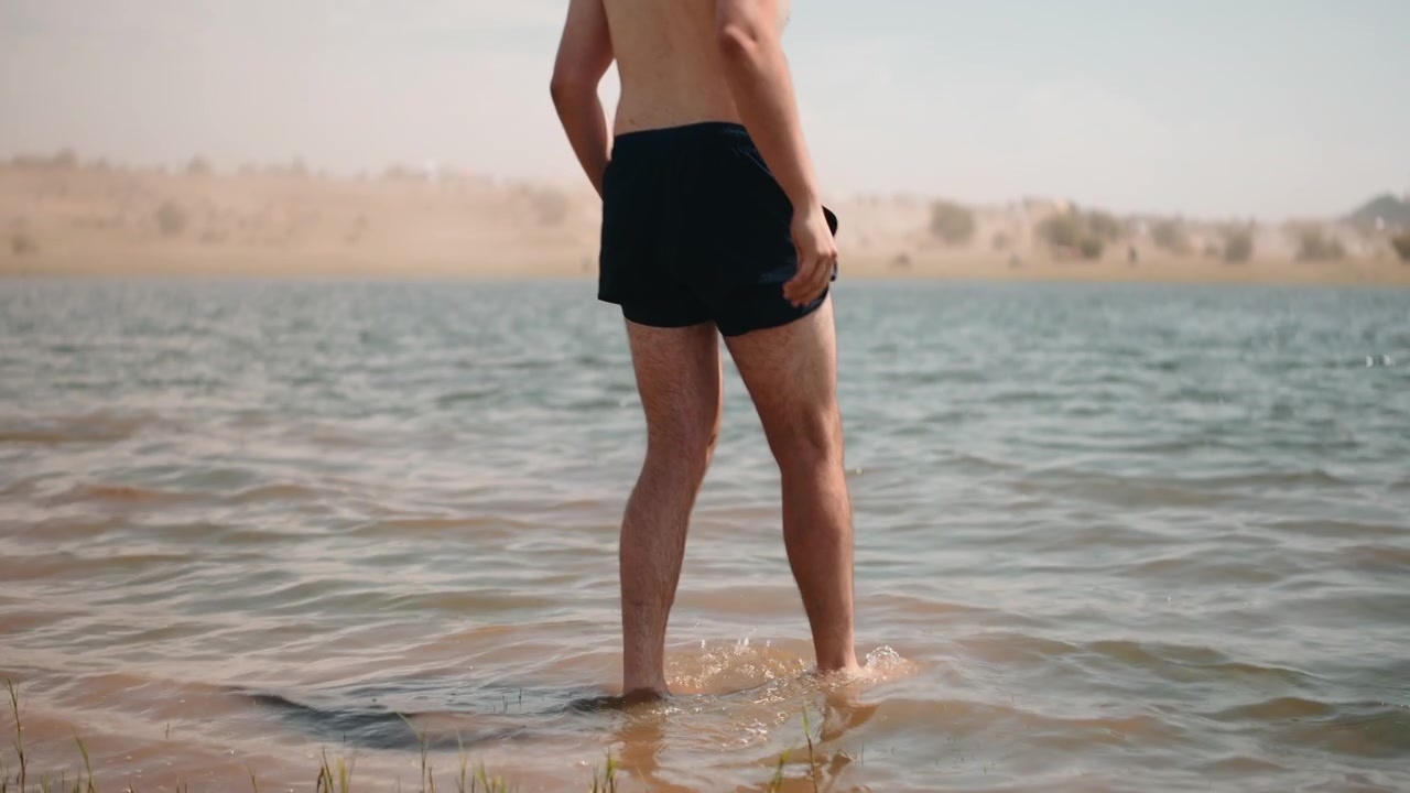Uomo che cammina a piedi nudi in un lago poco profondo nel deserto