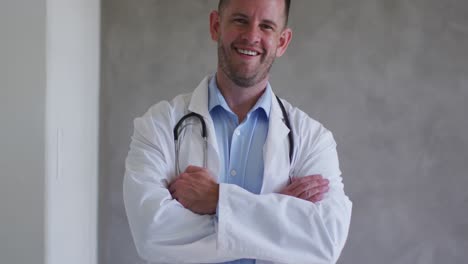 retrato de um médico caucasiano sorrindo com os braços cruzados