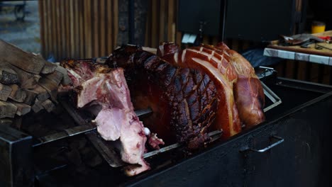 juicy beechwood smoked ham rotate above grill on skewer near firewood