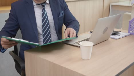 young businessman sitting and looking to document in folder for audit at the office, executive or manager looking report and information of finance on desk, man or accountant, business concept.