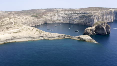 Zoom-Aéreo-De-Yates-Anclados-En-Una-Bahía-Escondida-De-Dwerja,acantilados,malta