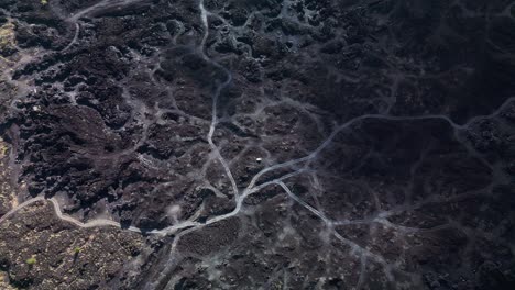 volcanic terrain with rough black rocks and roads weaving through the hardened lava fields in a surreal natural setting.