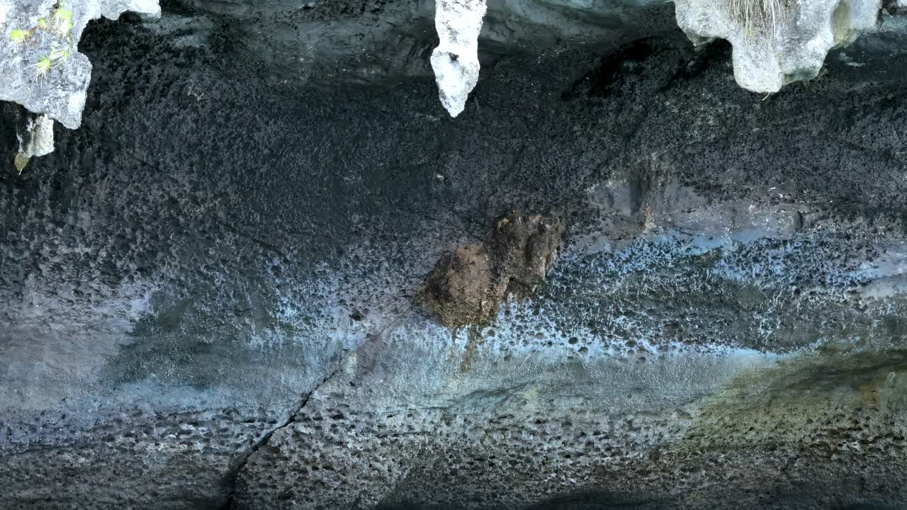Close-up view of limestone formations above vibrant turquoise water, showcasing natural textures and colors.