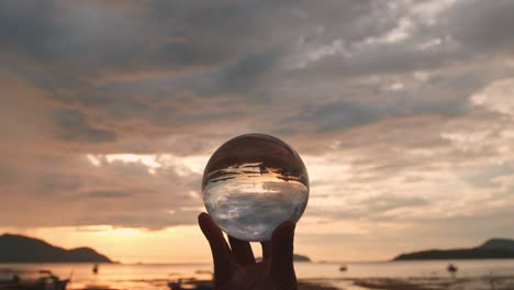 the hand held a crystal ball in sunset.