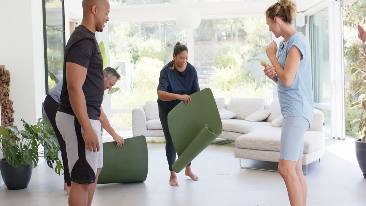 Forskellige venner samles til yoga, en indisk kvinde ruller en mørkegrøn måtte ud i en lys stue.