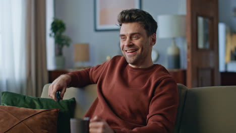 happy man enjoy tv show relaxing at home couch close up. guy looking television