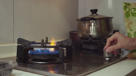 woman hand turns switch on and ignites a gas cooking pan