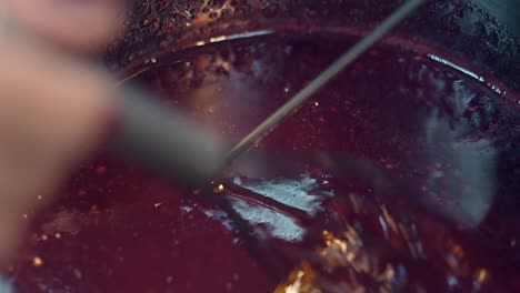 confectioner stirs future red berry syrup with small whisk