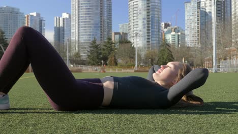 Fit-young-woman-doing-core-crunches-outdoor-in-park
