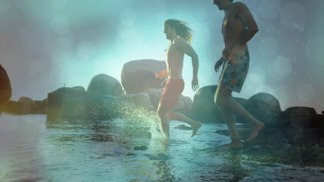 two men stepping into rocky coastal water at sunrise, with animated health icons and wave chart