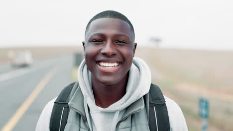 portrait of a smiling man with backpack on a road