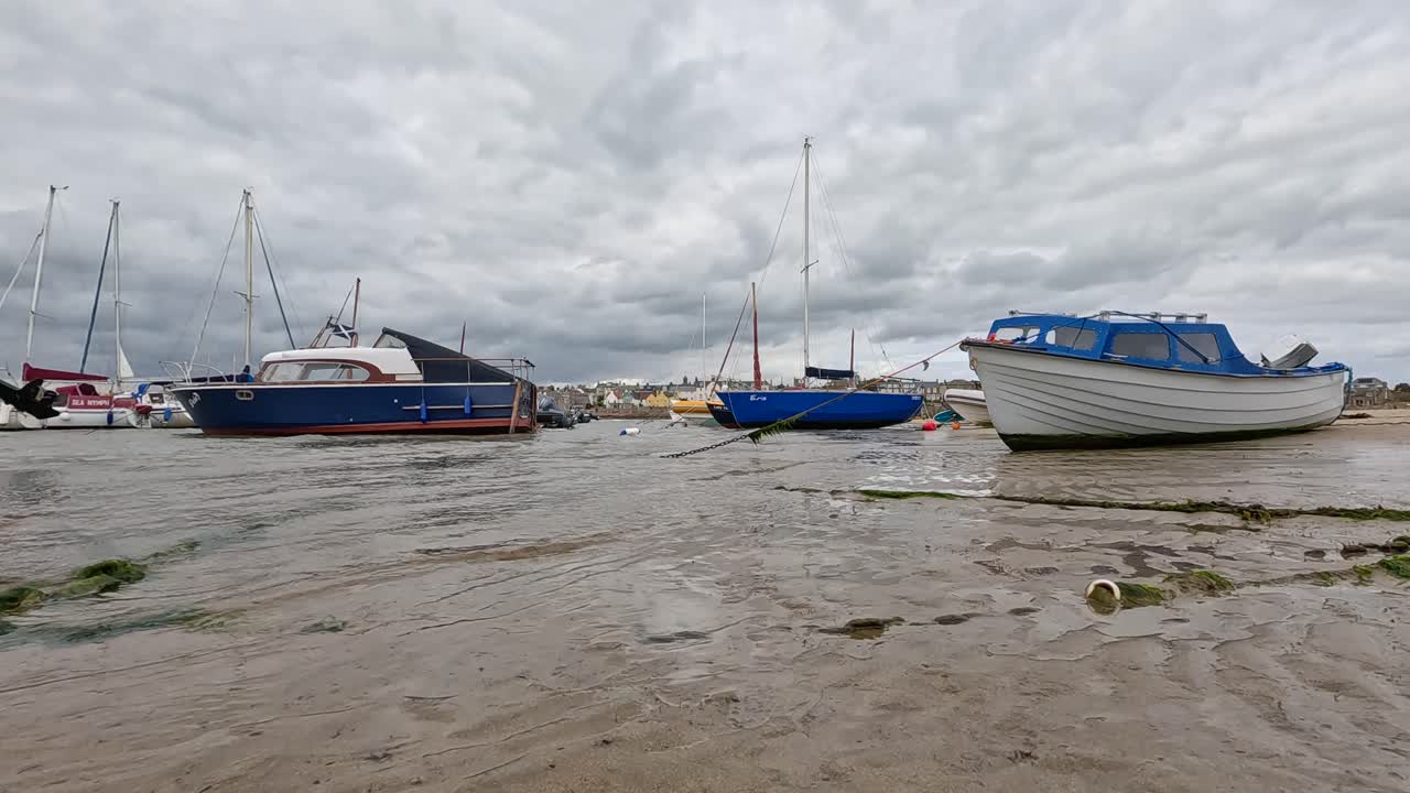 día nublado con barcos en la orilla arenosa