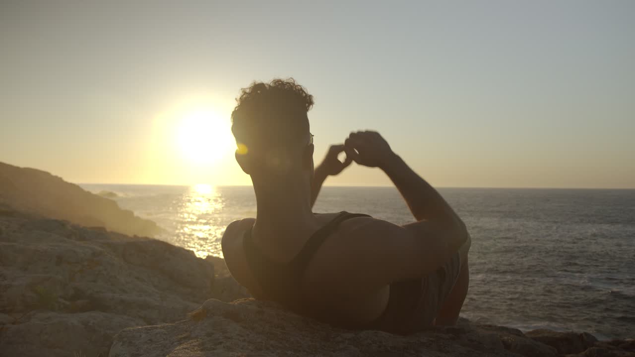Homme serein se reposant face à la mer en été au coucher du soleil