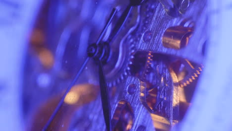 clock gears mechnism with second, hour, and minute hands under blue light