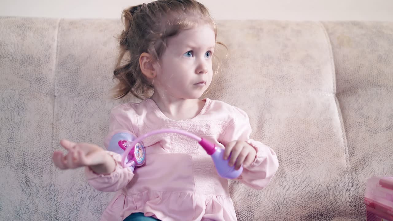 cu niña está jugando con un tonometro de juguete tratando de medir su propia presión