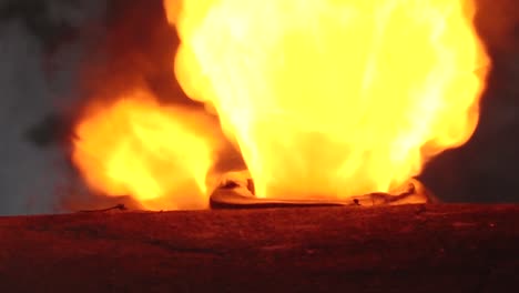 a large, intense flame is visible burning within a furnace, seen through a narrow slit