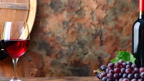 una botella de vino rojo al lado de un ramo de uvas y dos vasos de vino