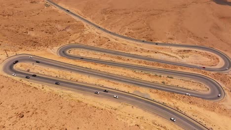 aerial view of day traffic going up and down a desert mountain winding road