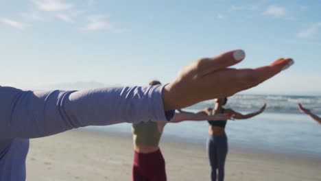grupo de diversas amigas practicando yoga en la playa