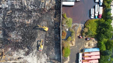 Vista-De-Arriba-Hacia-Abajo-De-Maquinaria-Pesada-Trabajando-En-El-Sitio-De-Escombros,-Excavadoras-Amarillas-Limpiando-El-Lugar-Quemado,-Toronto