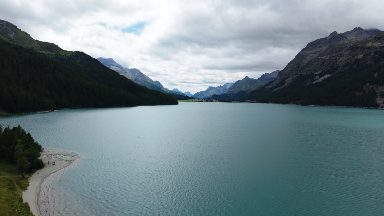 Drone pans over a Swiss alpine lake surrounded by forested mountains and clouds